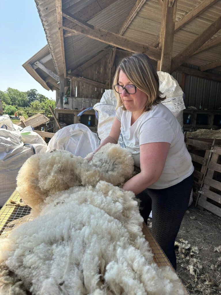 Femme manipulant de la laine de mouton dans un environnement de production durable.