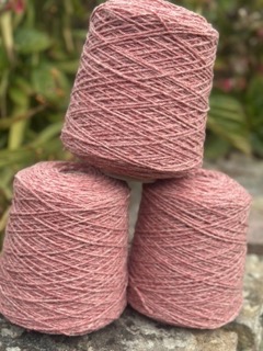Trois pelotes de laine rose, produites localement, provenant de moutons normands, prêtes pour l'artisanat.