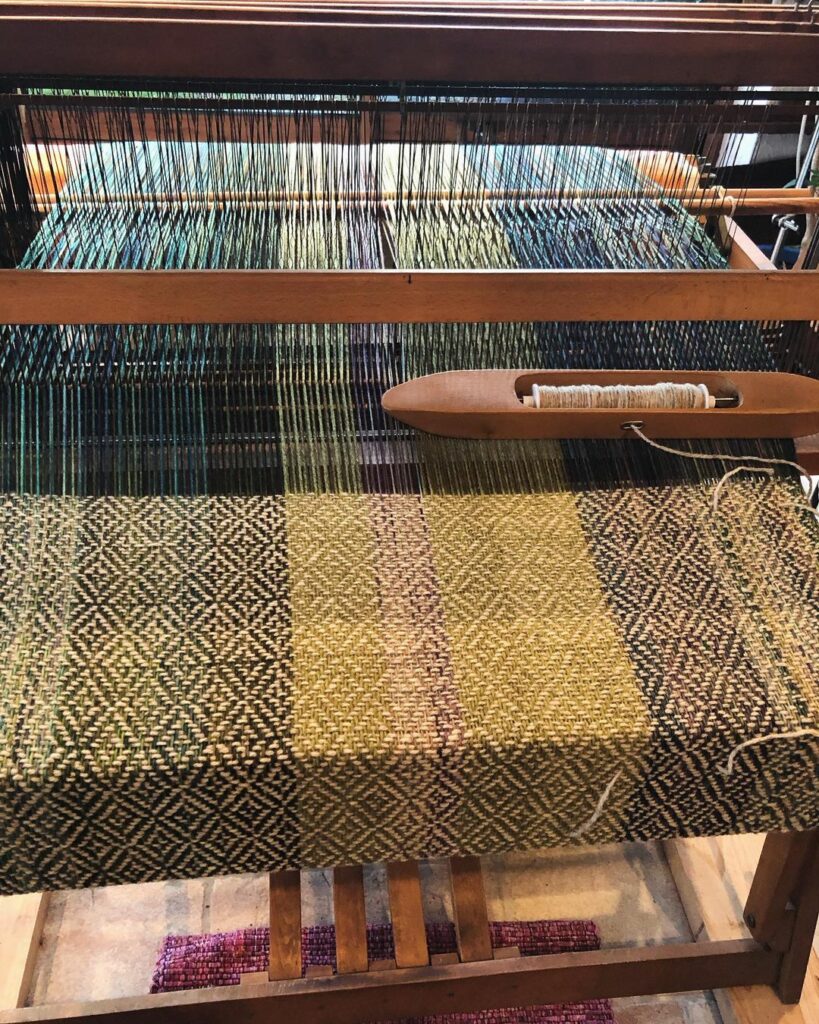 Métier à tisser montrant un tissage en laine aux motifs géométriques, reflet d'une production durable.
