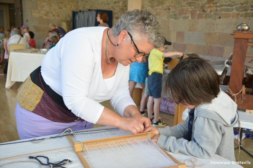 Atelier de tissage avec un adulte et un enfant, mettant en avant l'apprentissage des techniques de la laine.