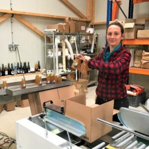 Femme empaquetant des produits à l'atelier de Laines sous les Pommiers, spécialisée dans la laine durable.