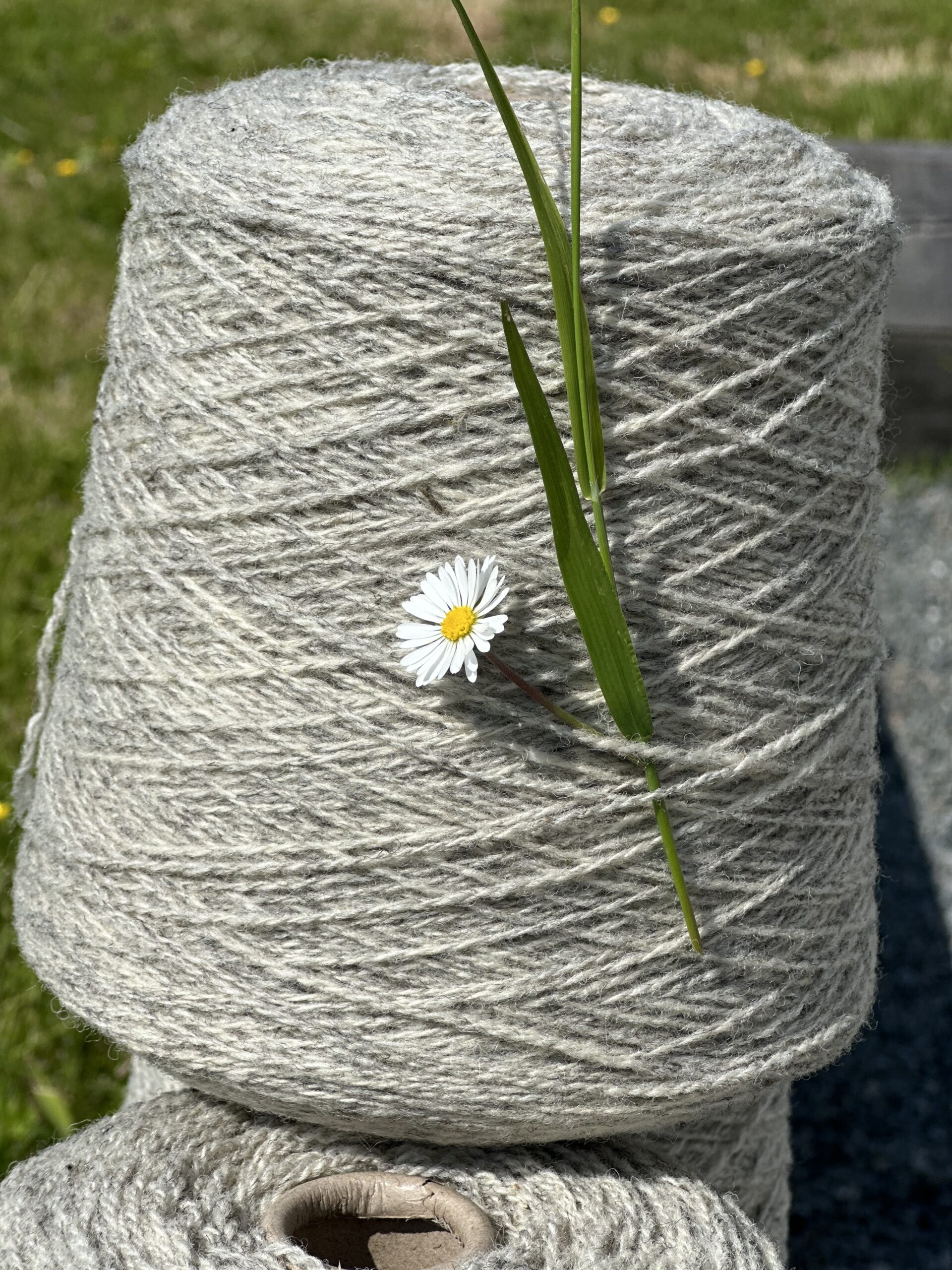 Pelotes de laine naturelle décorées d'une fleur, symbolisant la durabilité et l'artisanat de l'entreprise Laines sous les Pommiers.