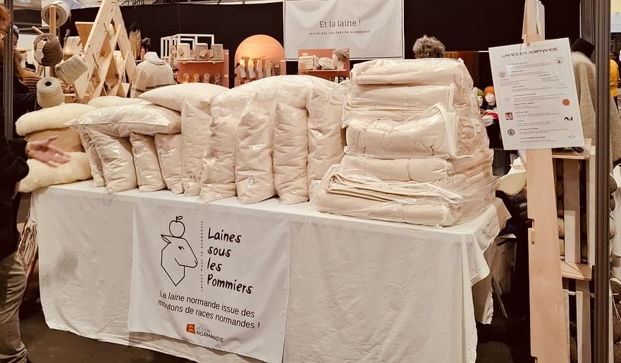 Stand de Laines sous les Pommiers avec des produits en laine normande, mettant en avant durabilité et respect de l'environnement.