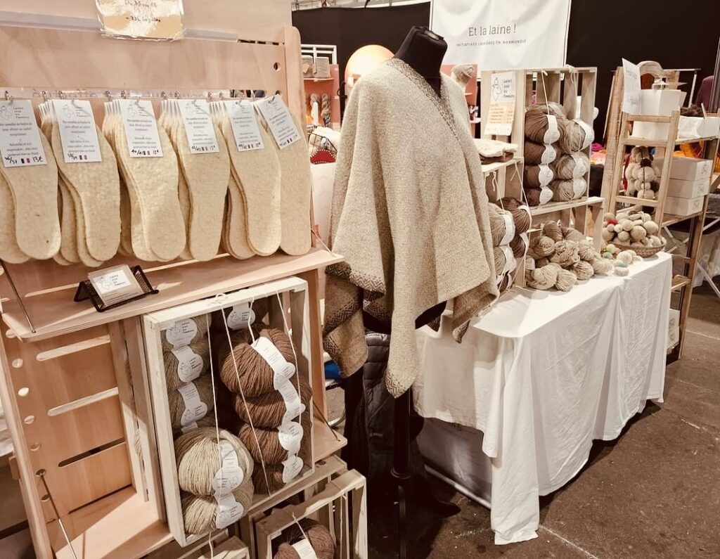 Exposition de produits en laine, dont des chaussons et des pelotes, soulignant la durabilité et l'artisanat de Laines sous les Pommiers.