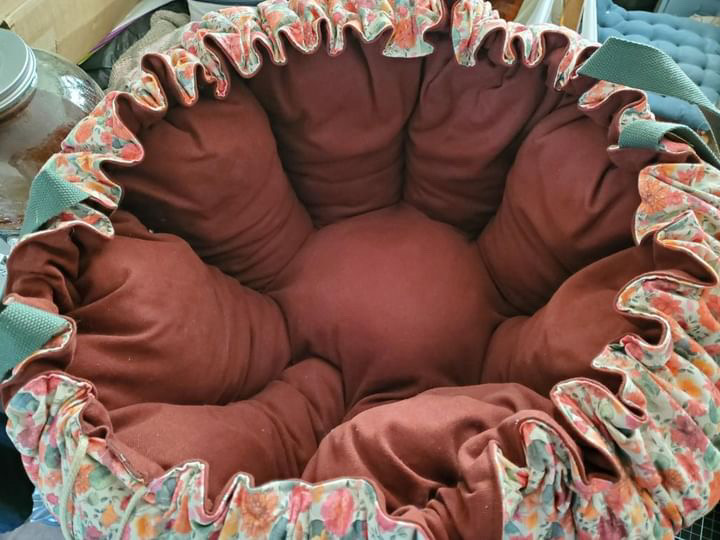 Panier en tissu avec un intérieur rembourré, orné de fronces florales et de poignées vertes. Durable et éco-responsable.