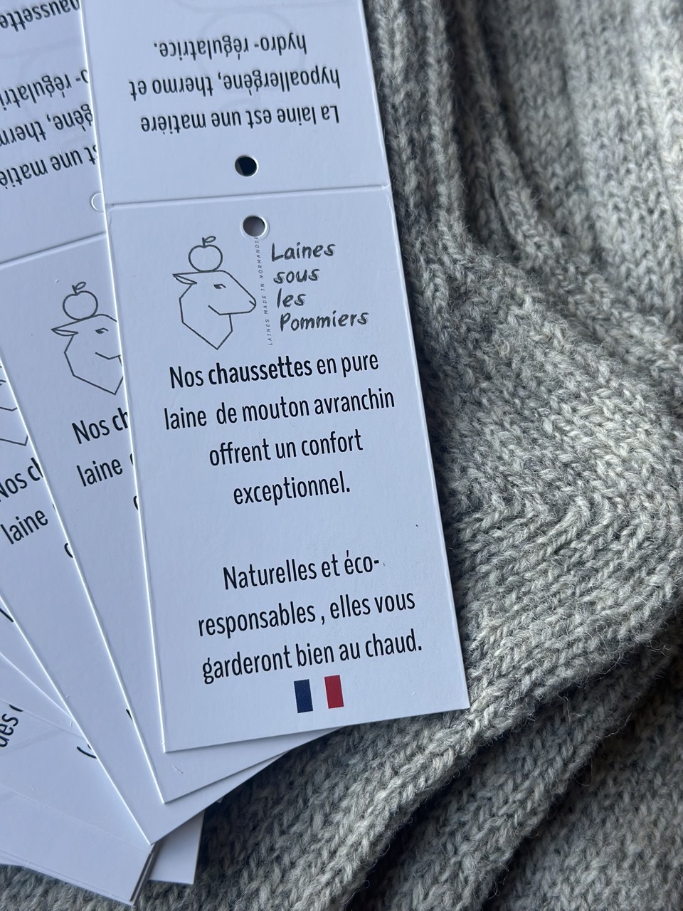 Chaussettes en laine d'Avranchin, confortables et écologiques, présentées avec étiquettes de la marque Laines sous les Pommiers.