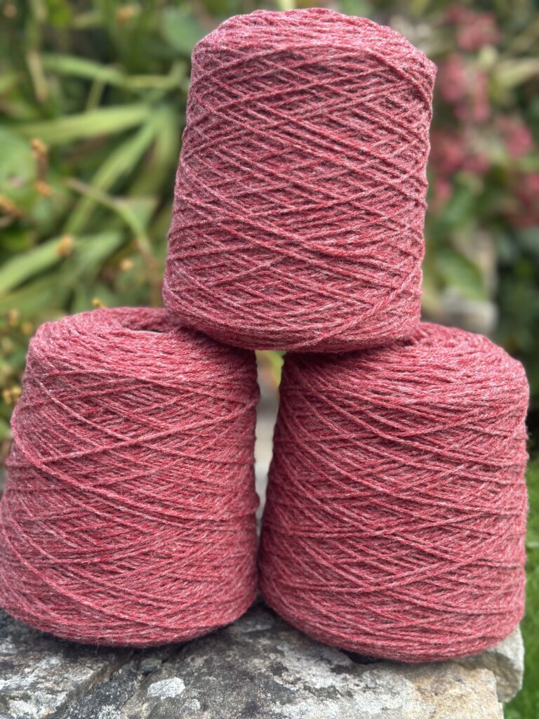 Pelotes de laine rouge, fabriquées à partir de la laine de moutons normands, enroulées et prêtes pour le tricot.