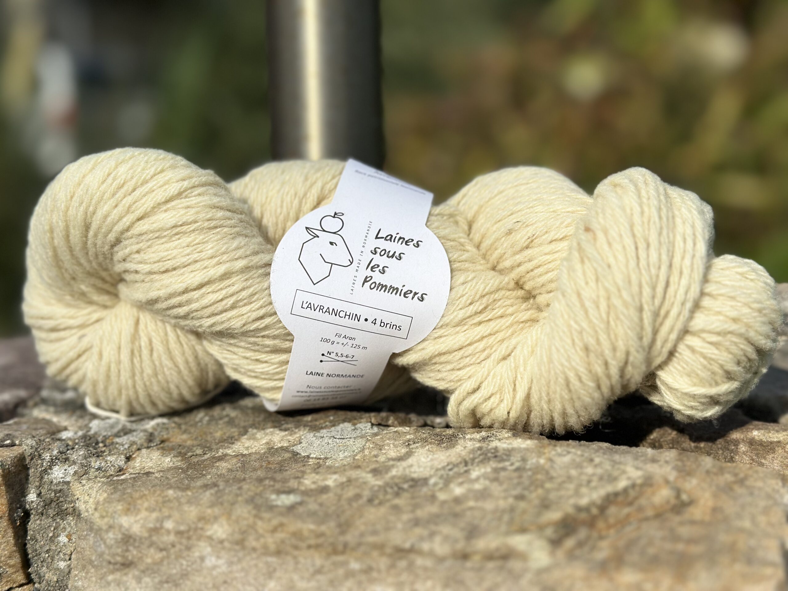 Écheveau de laine Aran de l'Avranchin, produit par Laines sous les Pommiers, sur fond de pierre naturelle.